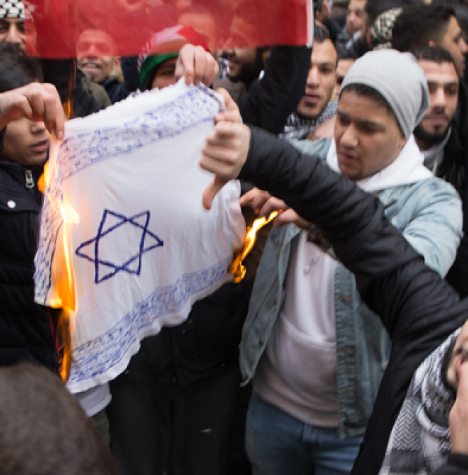 Teilnehmer einer Demonstration verbrennen am 10.12.2017 eine selbstgemalte Fahne mit einem Davidstern in Berlin im Stadtteil Neukölln. 