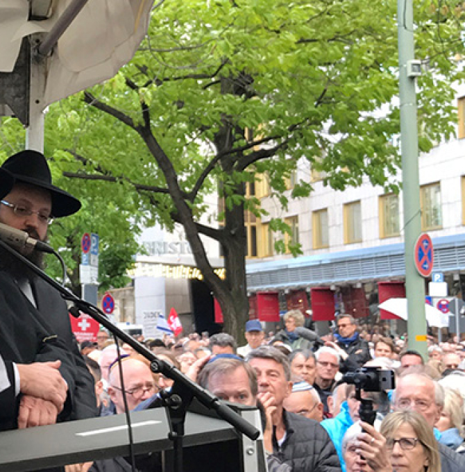 Das Bild zeit Volker Kauder mit einer Kippa auf dem Kopf, auf der Bühne stehend, hinter ihm zwei Vertreter der jüdischen Gemeinde Berlin, vor der Bühne eine Masse Menschen
