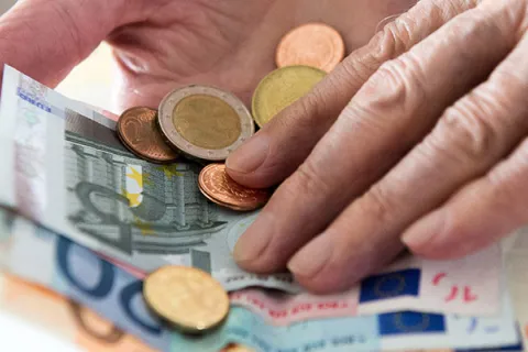 Eine Hand berührt Euro-Scheine und Münzen.