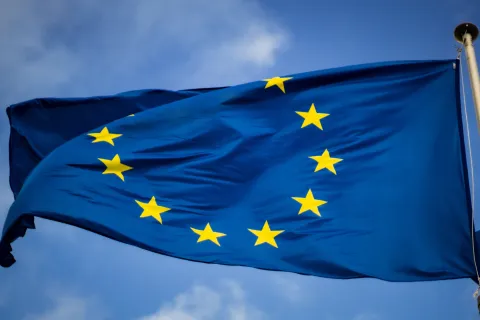Wehende Flagge der EU vor blauem Himmel.