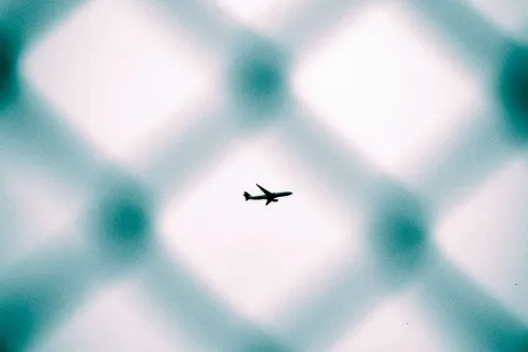 Startendes Flugzeuge durch einen Zaun gesehen