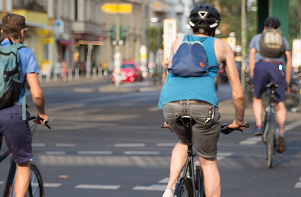 Drei Fahrradfahrer überqueren eine innerstädtische Kreuzung