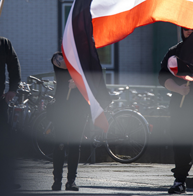 Auf dem Bild sieht man schwarz vermummte Personen auf einer NPD-Demonstration