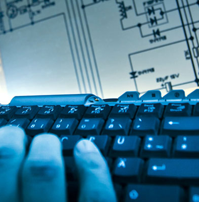 Ein Mann tippt auf einer Computer-Tastatur vor einem elektrischen Schaltplan.