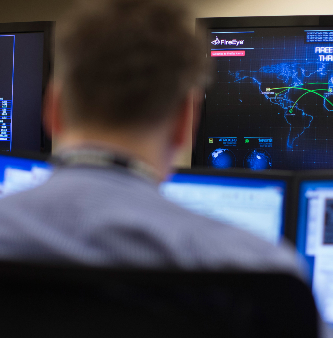 Mann, der vor mehreren Computerbildschirmen sitzt